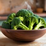fresh green broccoli in a wooden bowl on a rustic kitchen countertop. The broccoli is glistening with freshness, with steam rising from a small portion, suggesting a healthy and delicious meal.